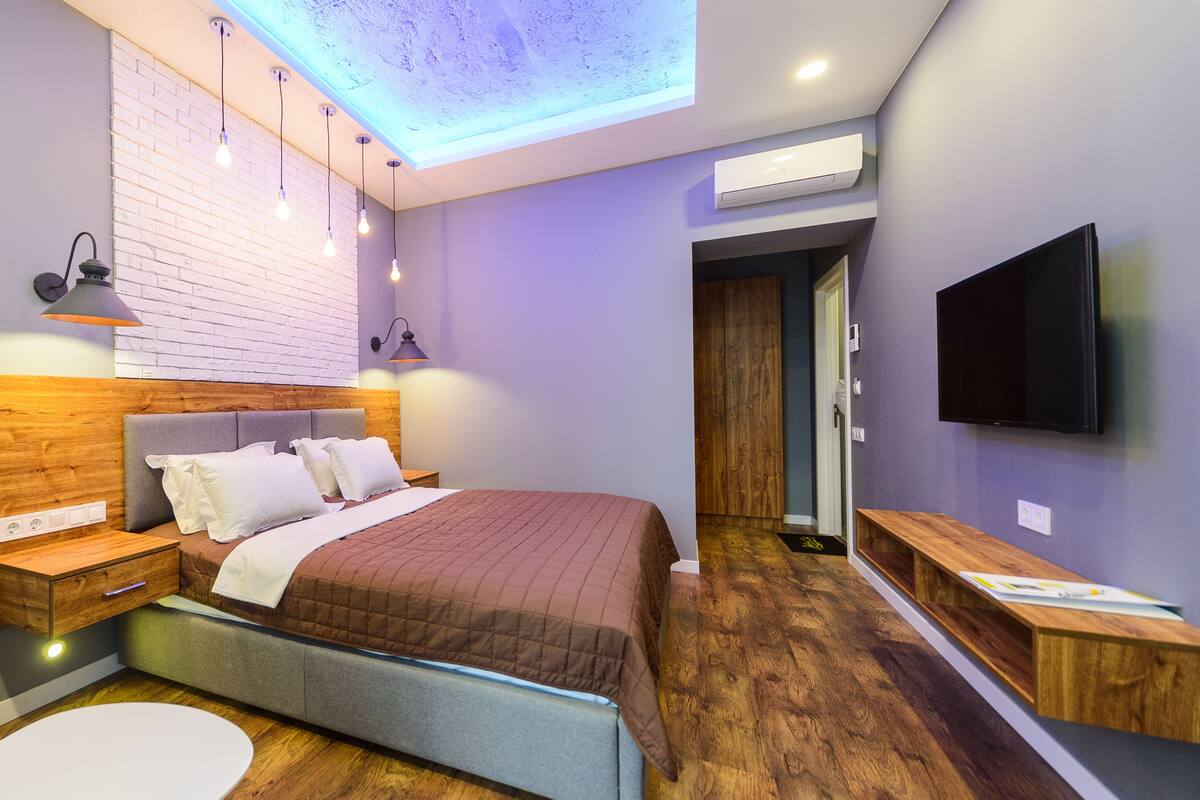 A modern bedroom with a bed, bedside tables, a TV, and a skylight.