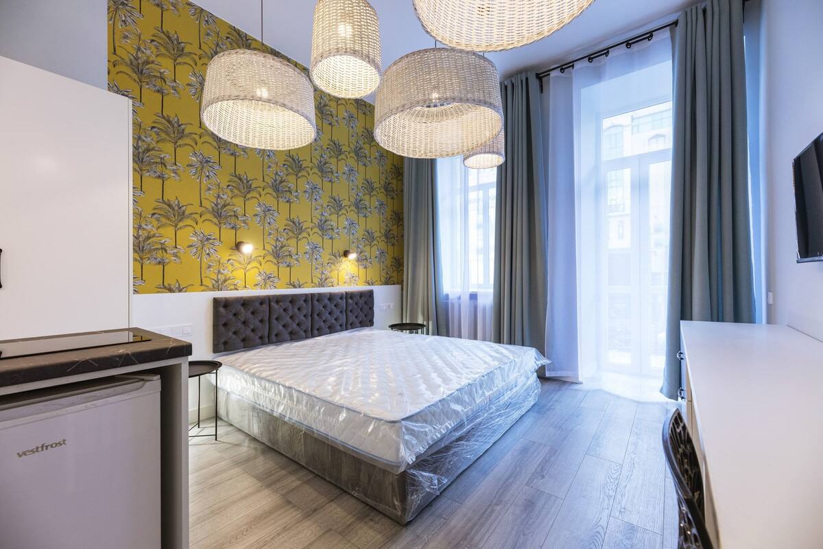 A modern bedroom with a large bed, a bedside table, a wardrobe, and a built-in TV.