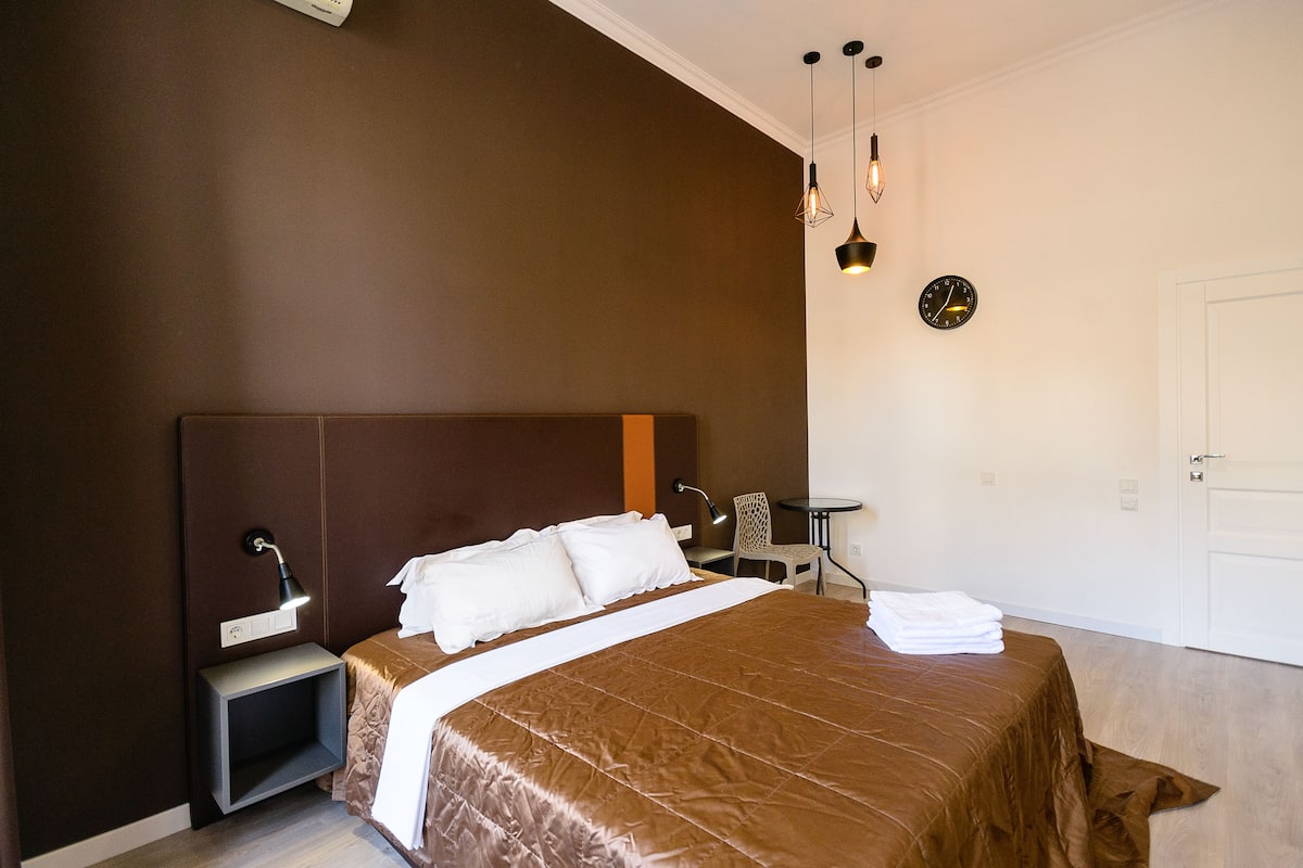 A bedroom with a large bed, bedside tables, a desk, and a chair.