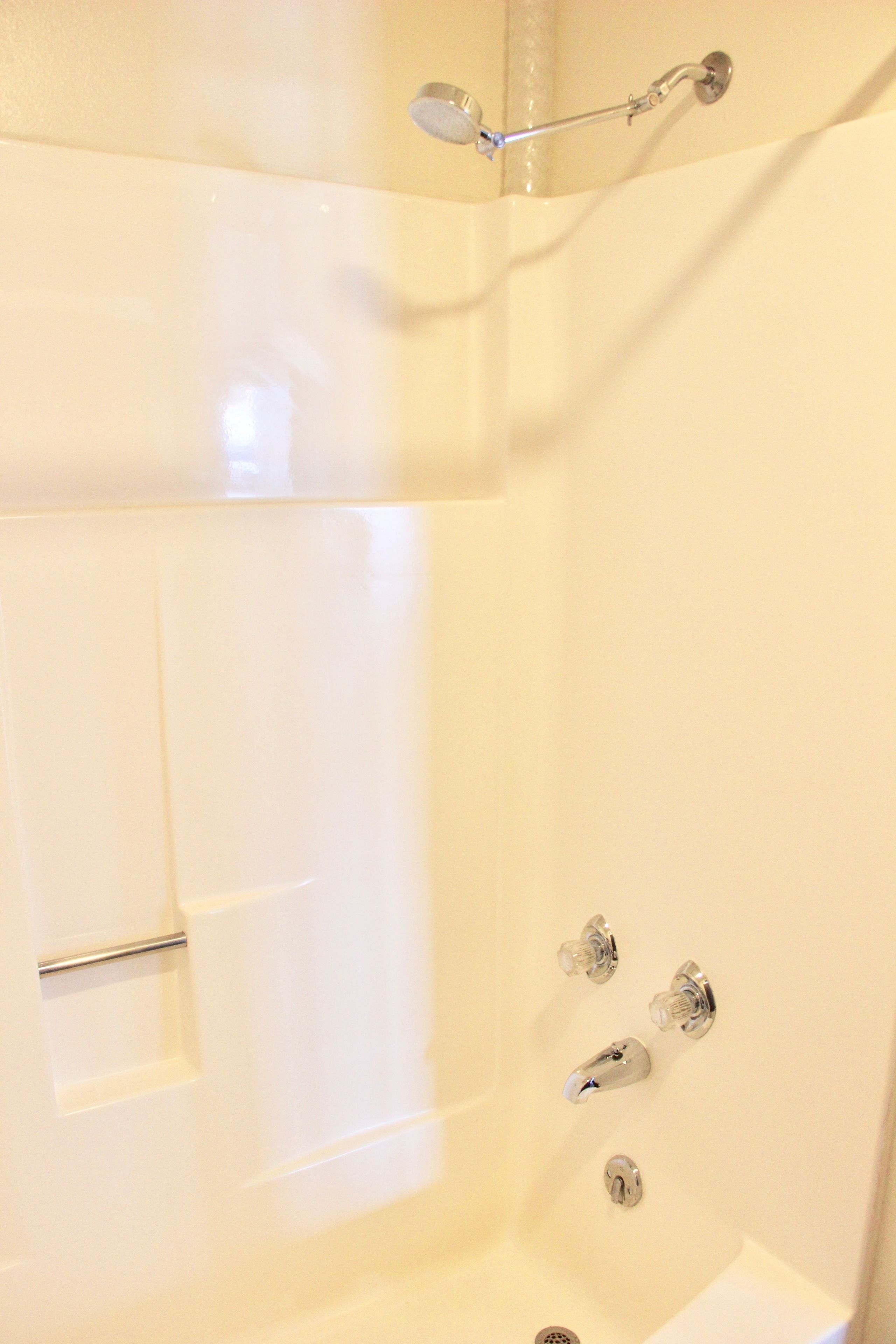 A bathroom with a bathtub, a showerhead, and a faucet.