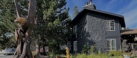 A two-story stone house with a large tree in the front yard.