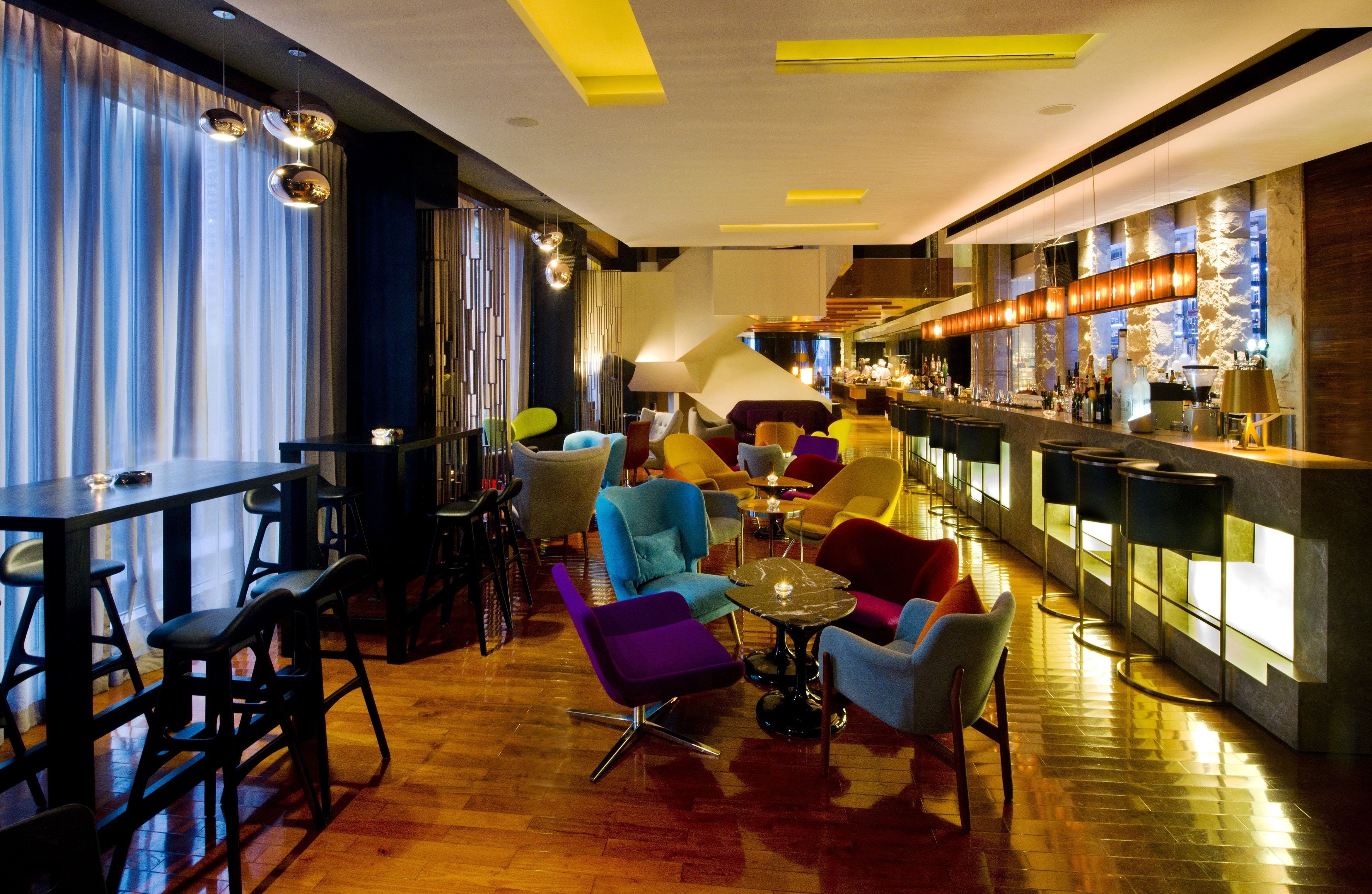 Un área de bar moderna con mostrador, taburetes y asientos coloridos.