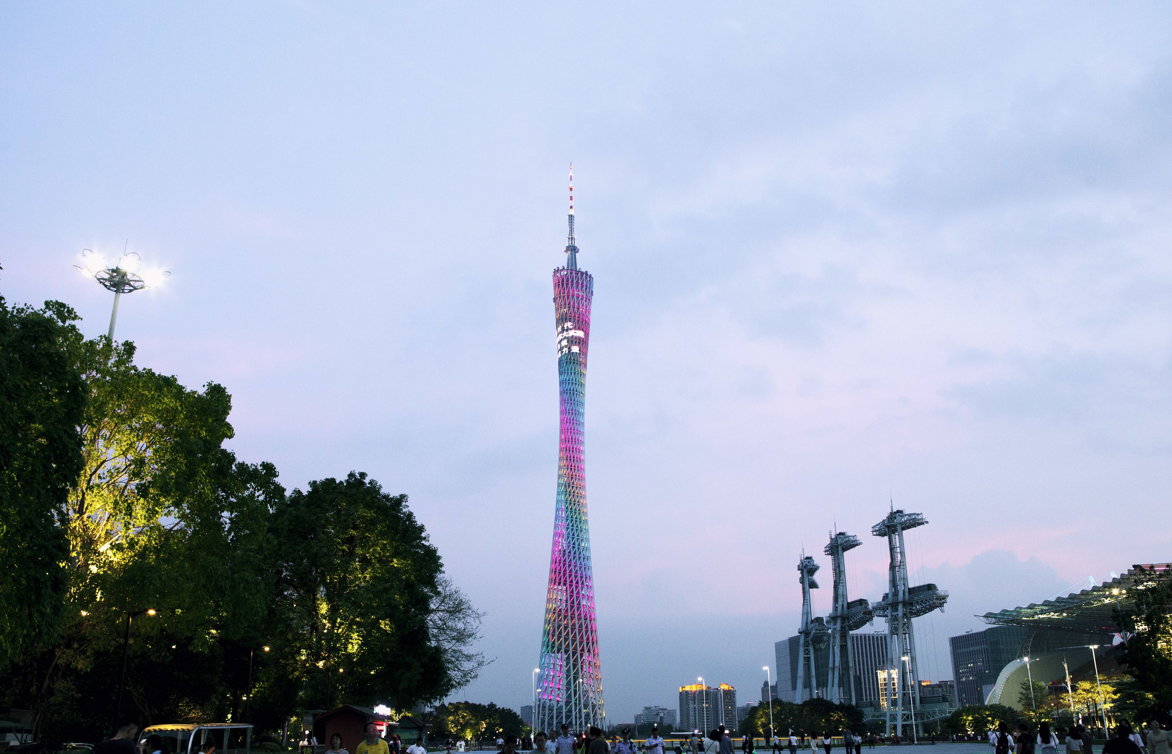A tall tower with a unique lattice structure, surrounded by trees and other buildings.