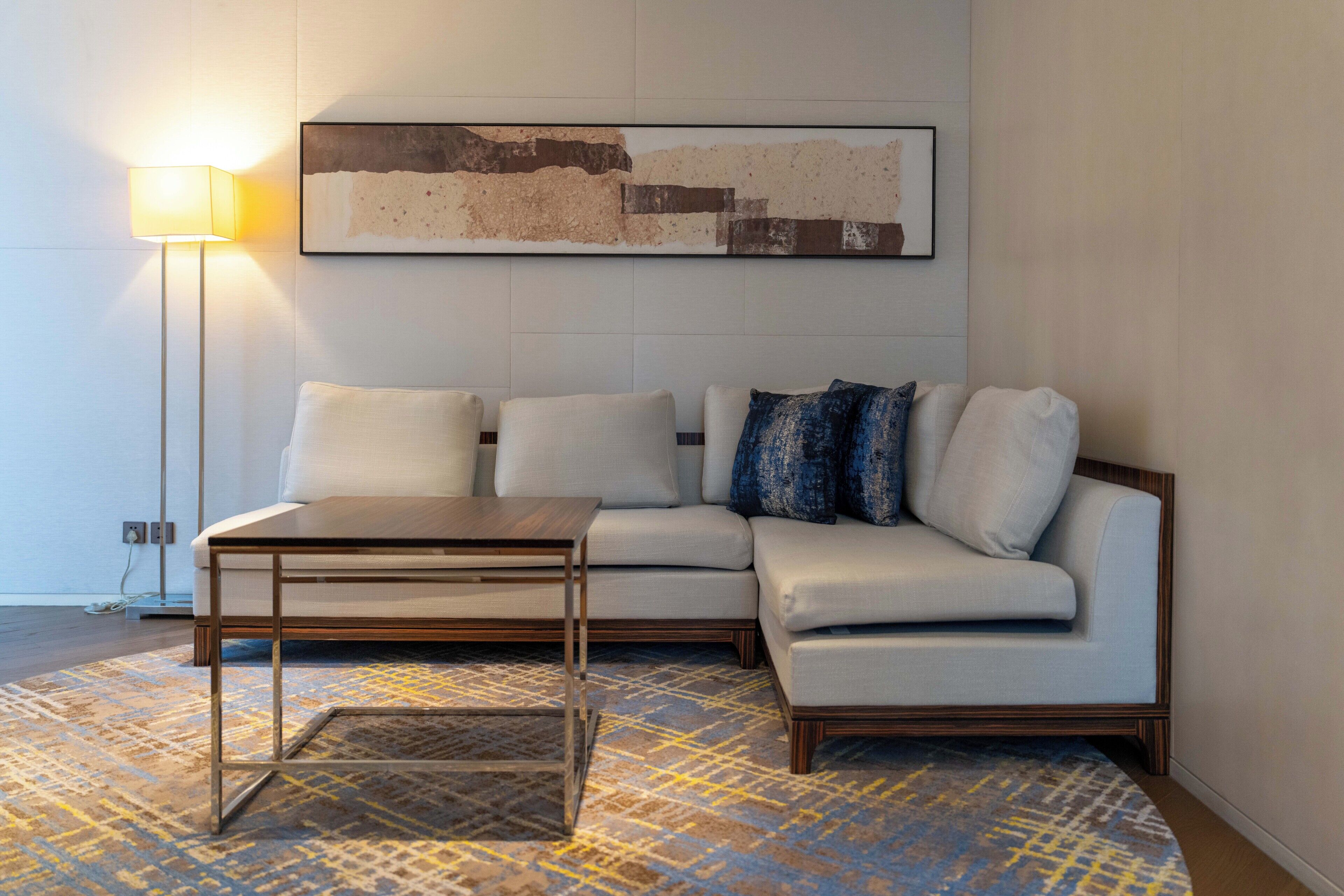 A modern living room with a sectional sofa, a coffee table, a floor lamp, and a patterned rug.