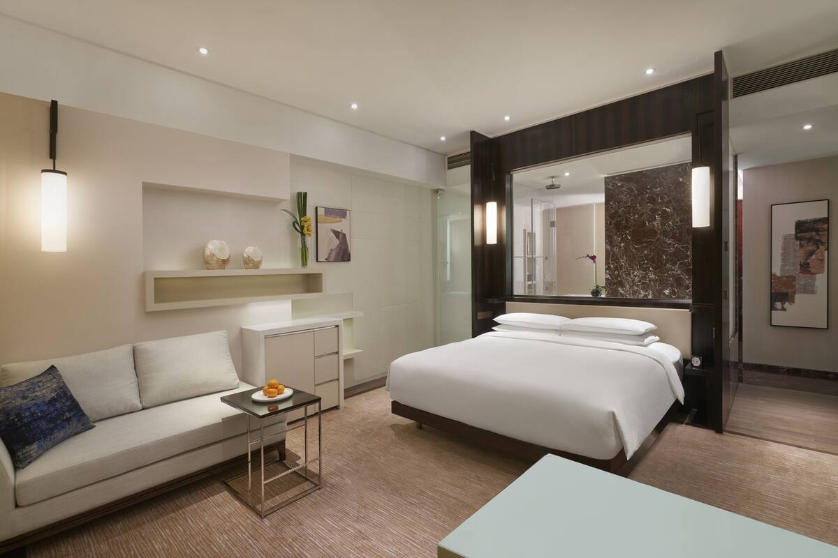 Een moderne hotelkamer met een groot bed, een sofa, een tafeltje en een spiegel.