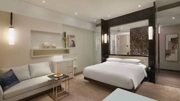 A modern hotel room with a large bed, a sofa, a small table, and a mirror.