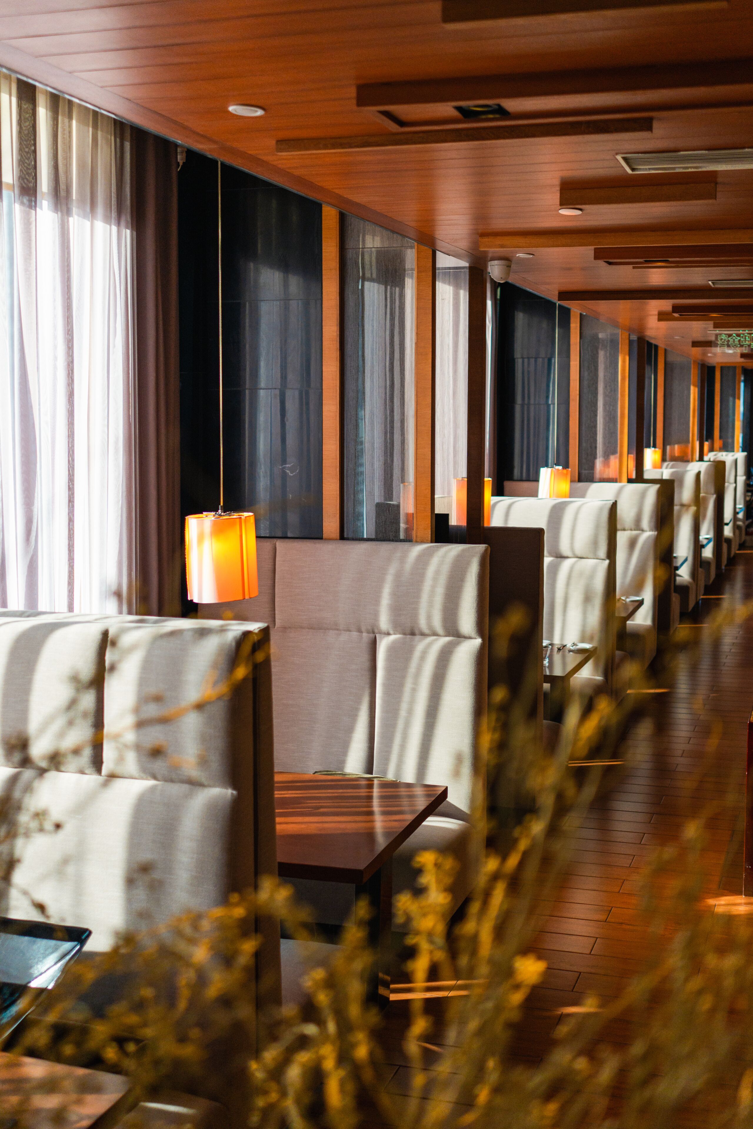 A row of hotel rooms with large windows, a wooden ceiling, and a modern interior design.