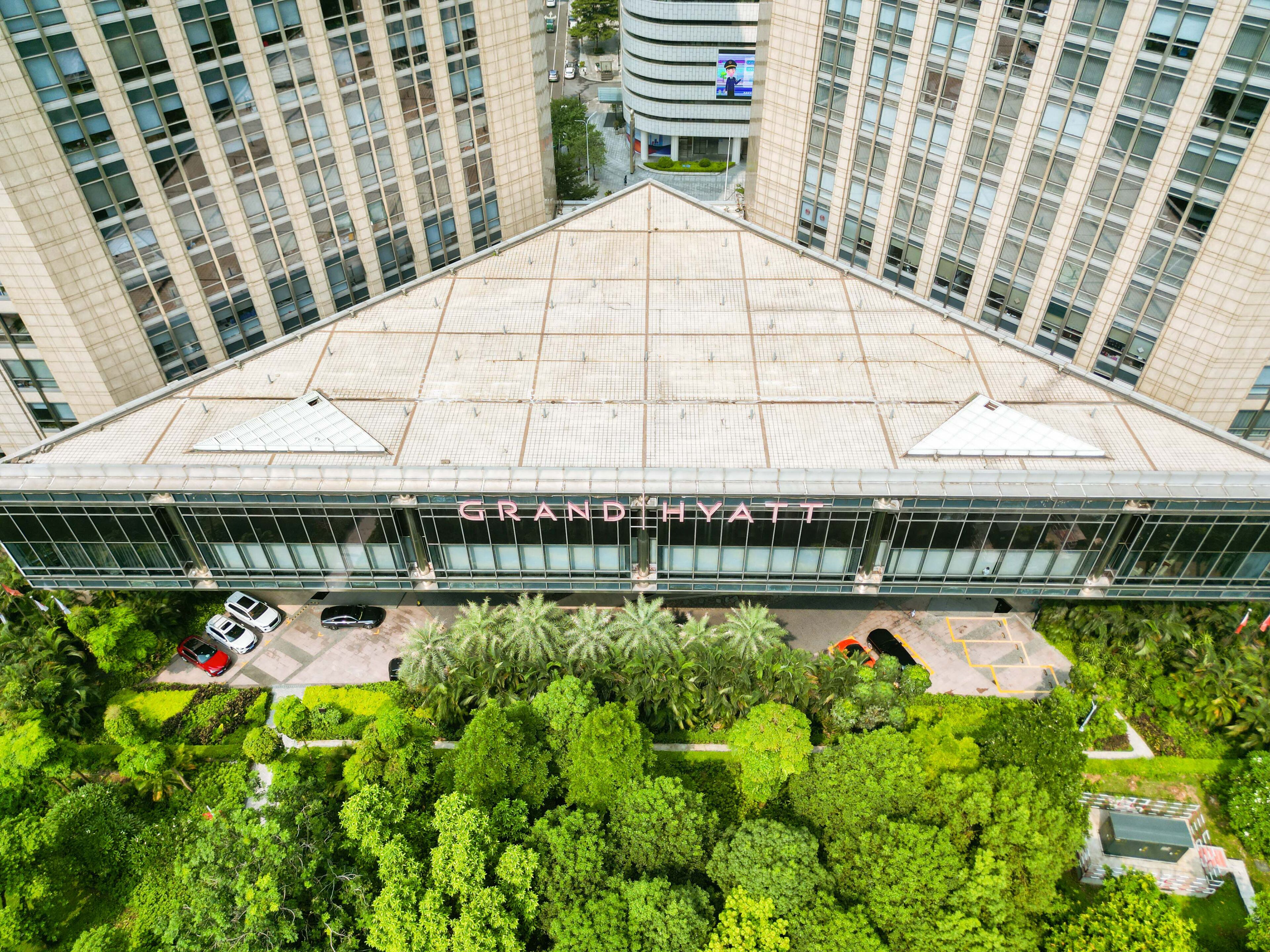 A modern hotel with a prominent glass facade and a rooftop terrace.