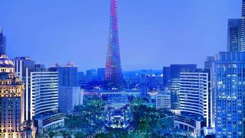 A cityscape with a prominent tower, surrounded by modern buildings and a park area.