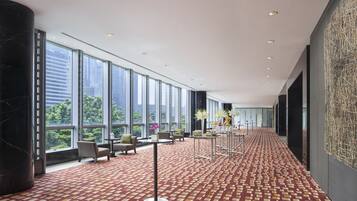 A spacious hallway with large windows, a patterned carpet, and modern furniture.