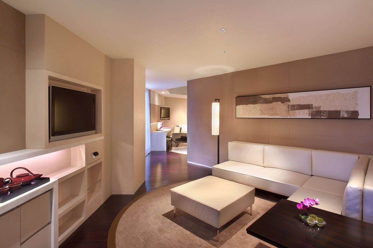 Een moderne hotelkamer met een flatscreen televisie, een bank, een bijzettafeltje en een schilderij aan de muur.