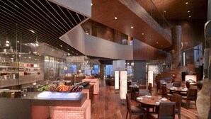 Un restaurante moderno con una zona de bar central, suelo de madera y mobiliario contemporáneo.