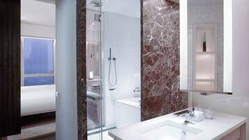 A modern bathroom with a glass shower enclosure, a marble-topped sink, and a large mirror.
