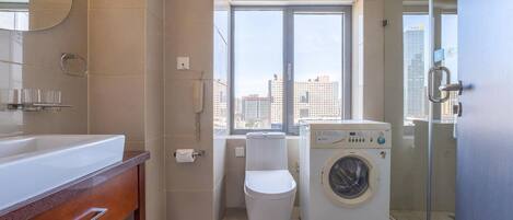 A modern bathroom with a large window, a washing machine, and a toilet.