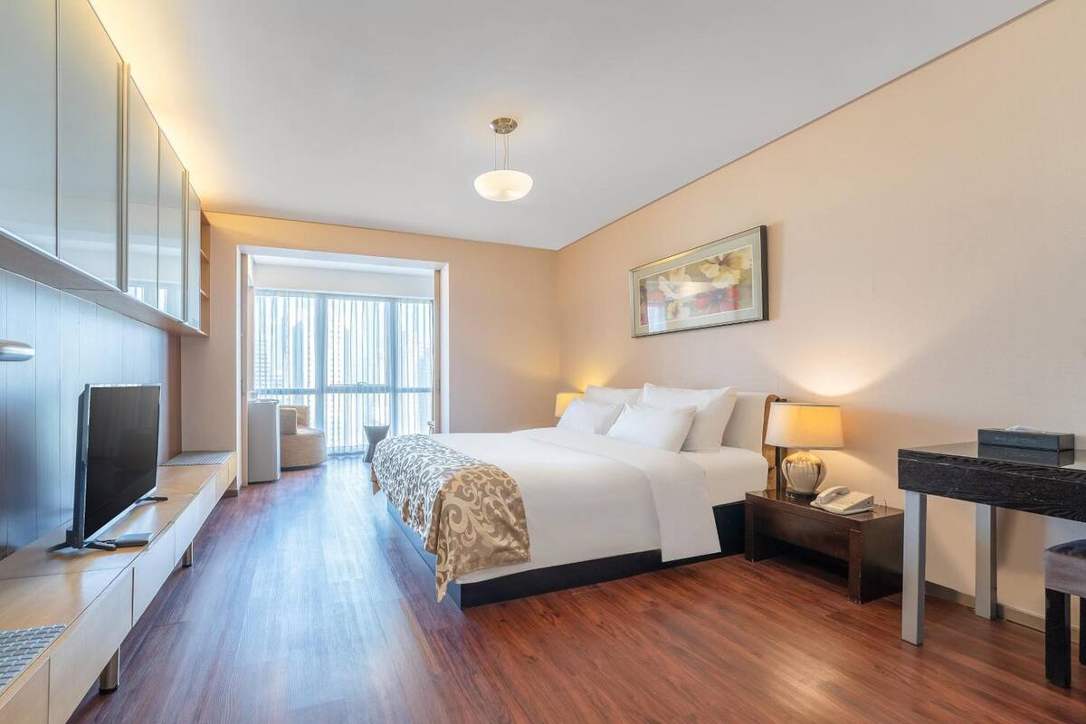 Una camera d'albergo moderna con un grande letto, un comodino con lampada, una scrivania e una televisione.
