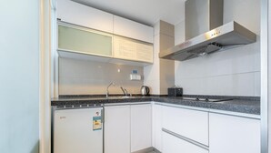 Een moderne keuken met witte kasten, een zwart aanrecht en een rvs afzuigkap.