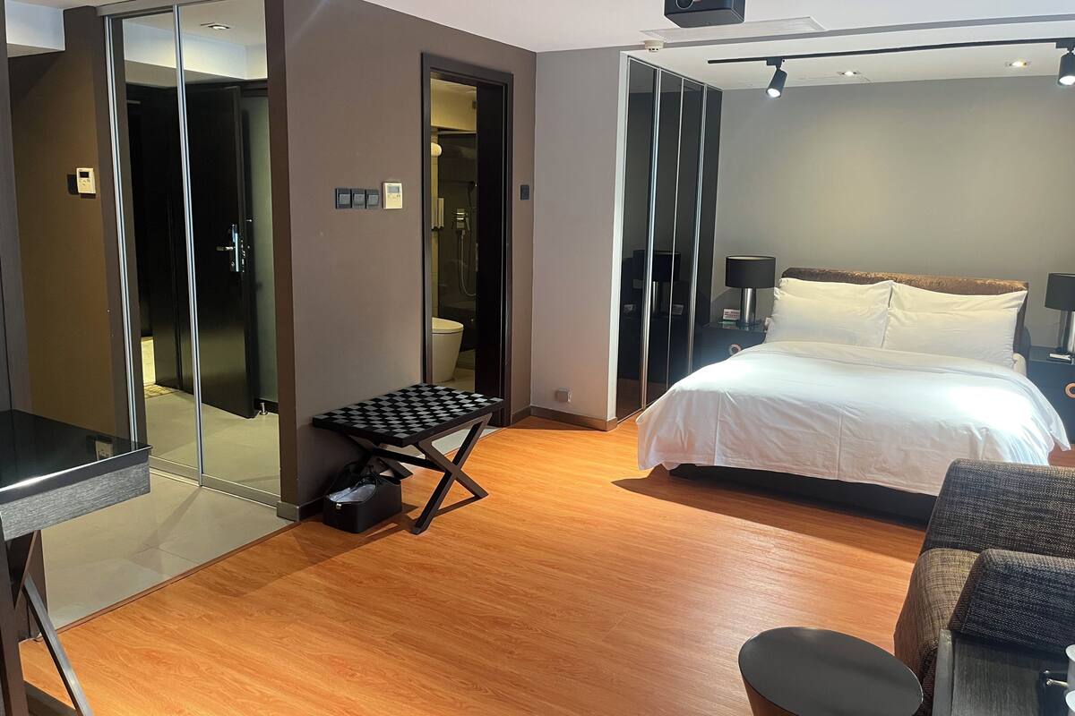 Una camera d'albergo con un letto, una scrivania, una sedia, un tavolino e uno specchio.