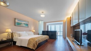 Hotelkamer met een groot bed, een televisie, een bureau met lamp en een schilderij aan de muur.