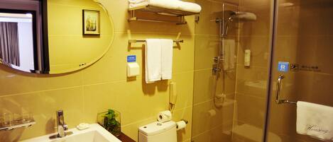 Baño con lavamanos, inodoro y ducha. Se observa un perchero con toallas y un cuadro en la pared.