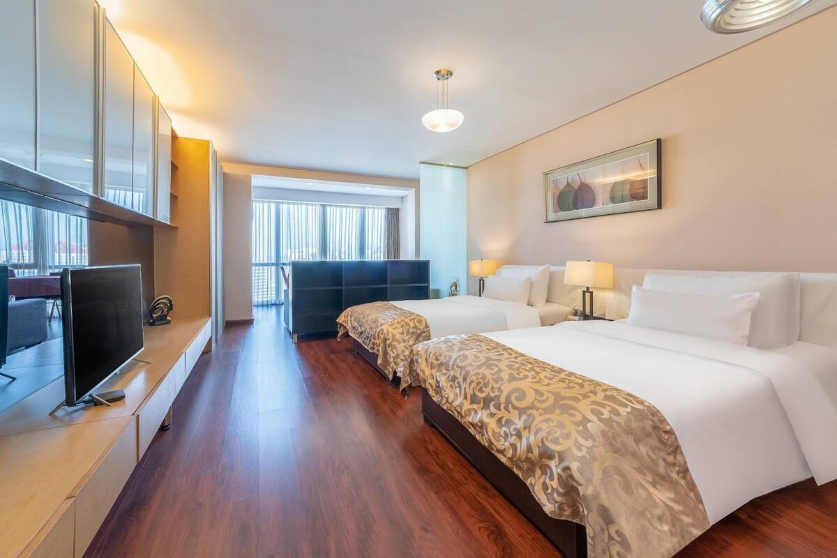 Camera d'albergo con un ampio letto, una televisione, una scrivania e una finestra con tende.