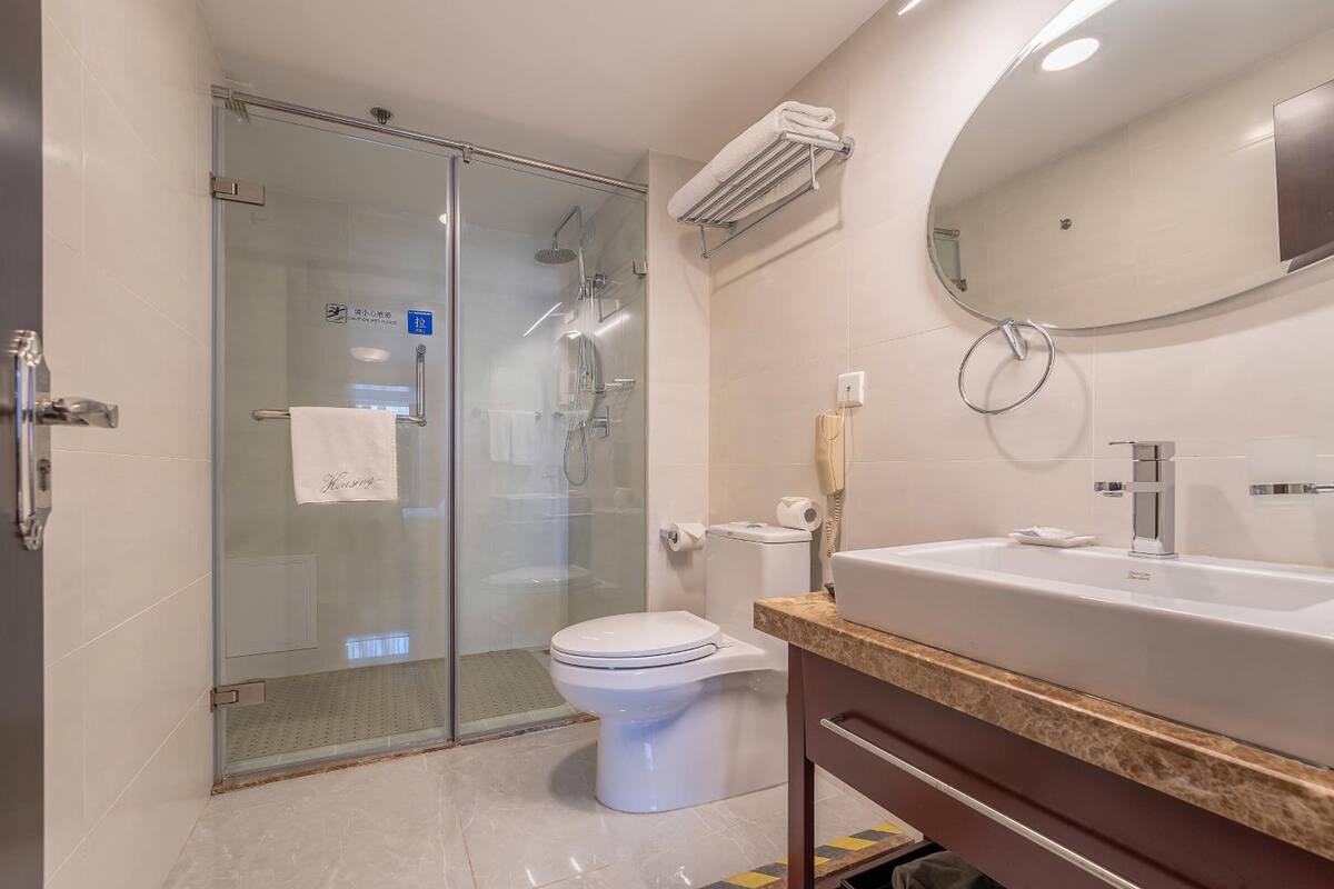 Un bagno moderno con doccia vetro, un water bianco e un lavandino capiente con specchio sopra.
