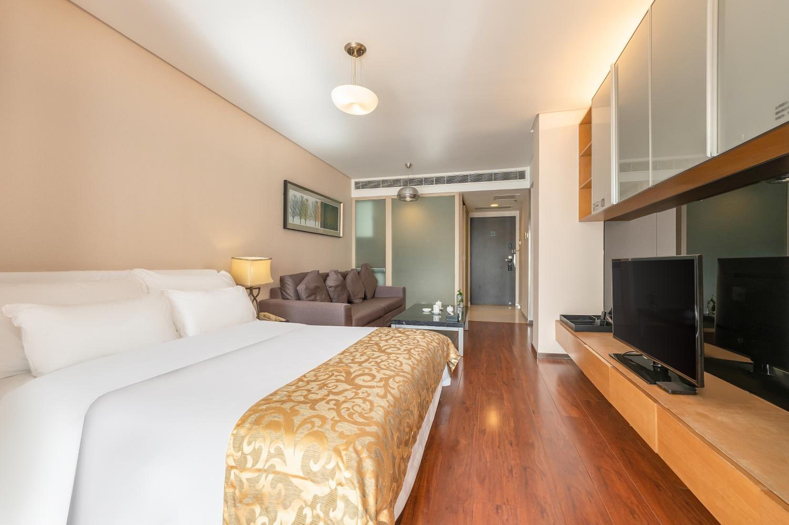 Ein Hotelzimmer mit einem großen Bett, einer Couch, einem Fernseher und einem Schreibtisch.