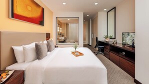A hotel room with a large bed, a desk, a television, and a mirror.