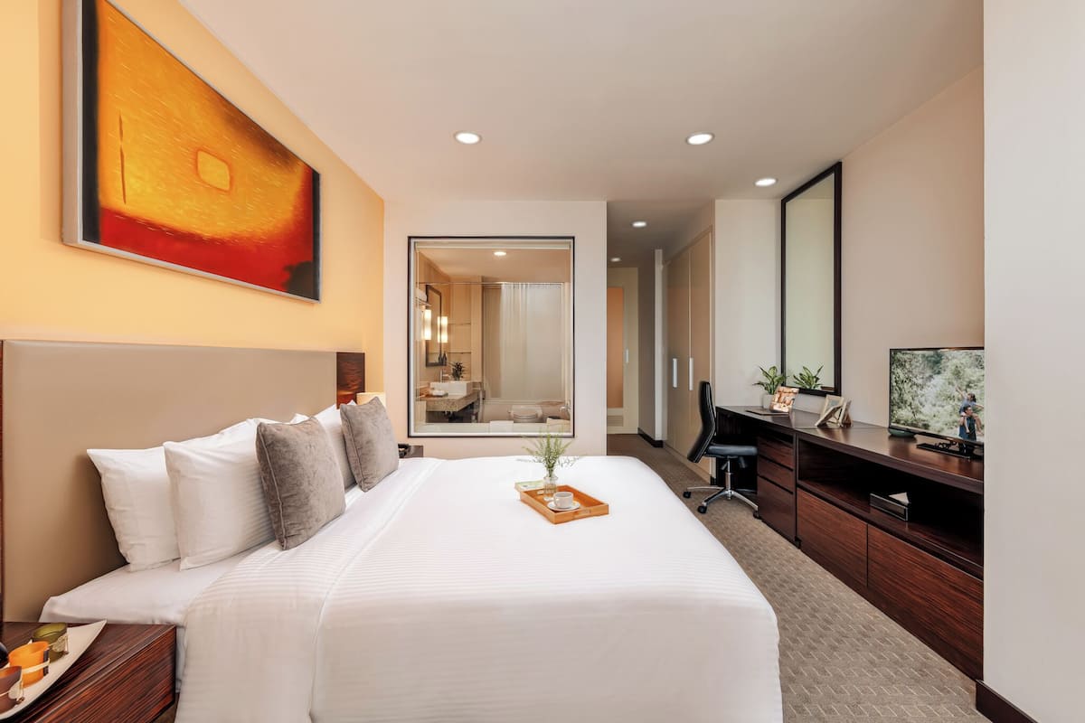 Een hotelkamer met een groot bed, een bureau, een televisie en een spiegel.