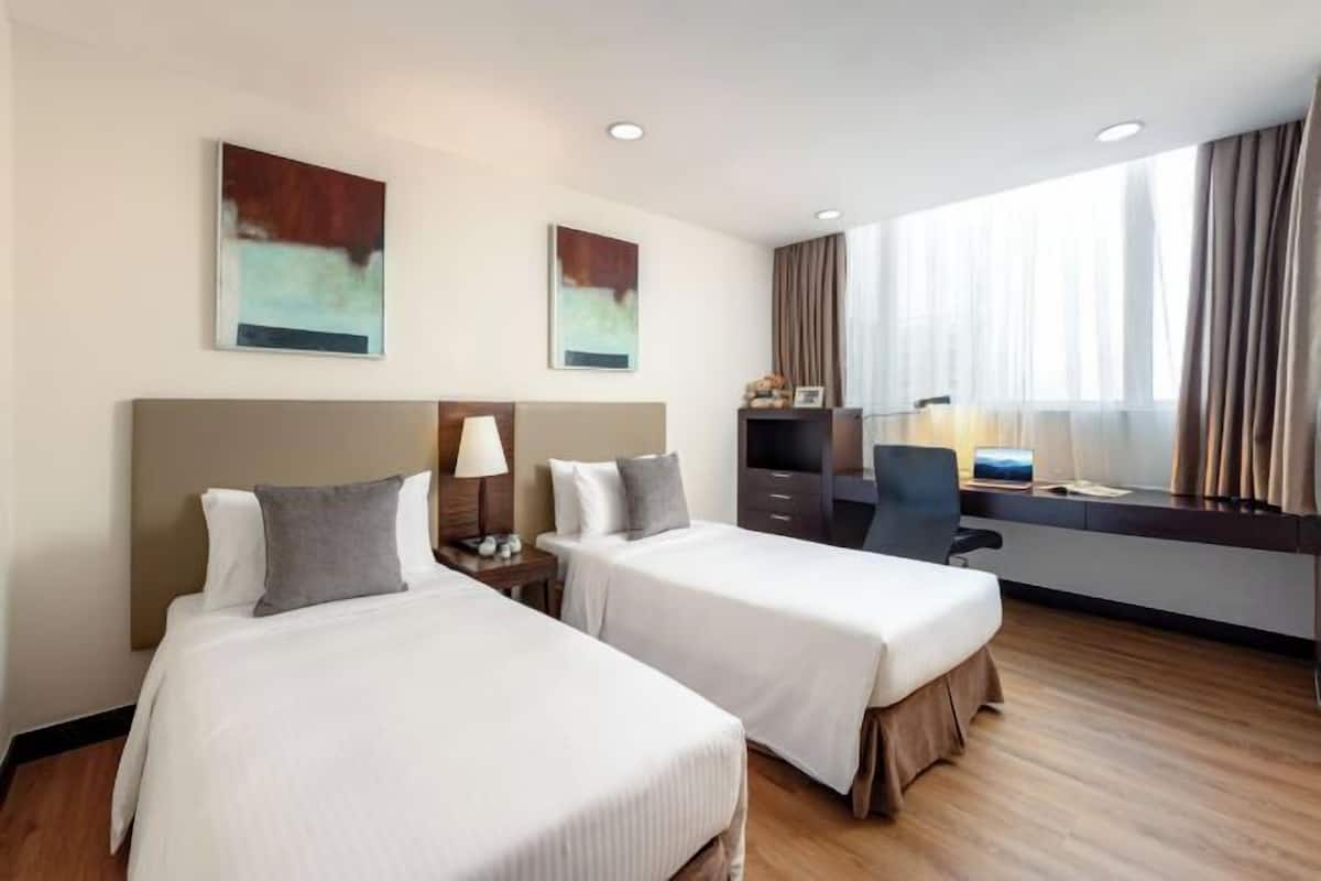 Een hotelkamer met twee bedden, een bureau, een stoel en kunst aan de muren.