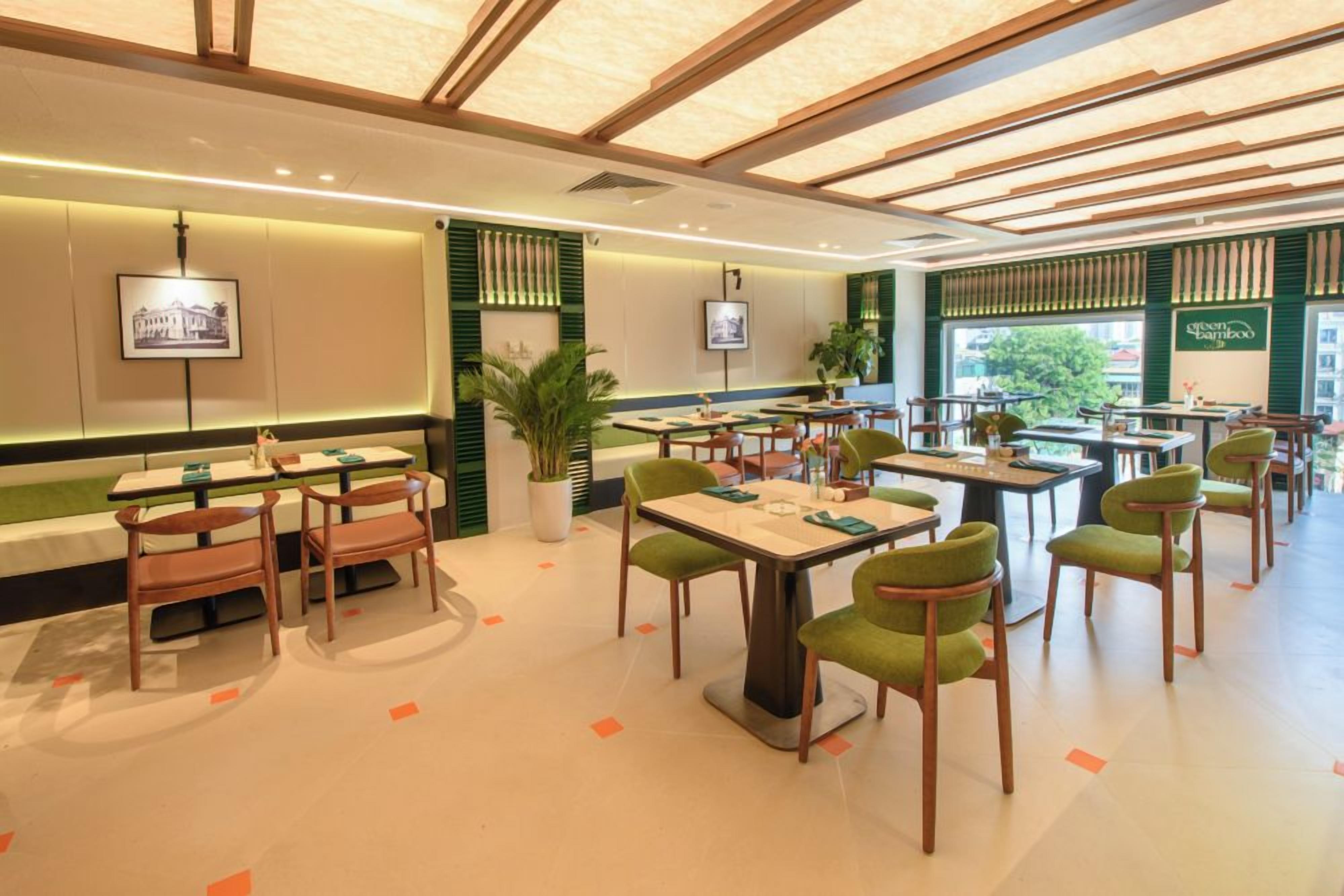 A restaurant with multiple tables and chairs, some with green upholstery.