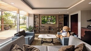 A modern living room with a large TV, comfortable seating, and a view of the outdoors.