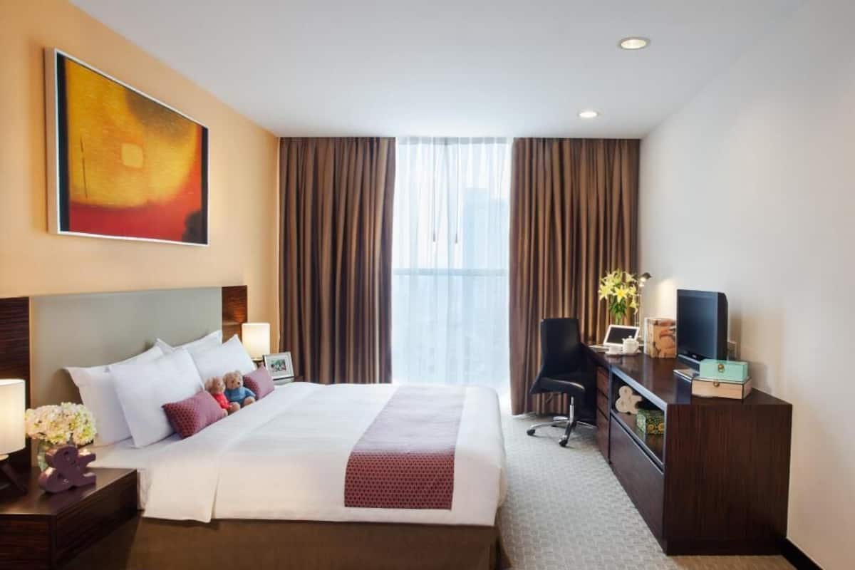 Hotelkamer met een groot bed, een bureau, een stoel, een televisie en een raam met gordijnen.