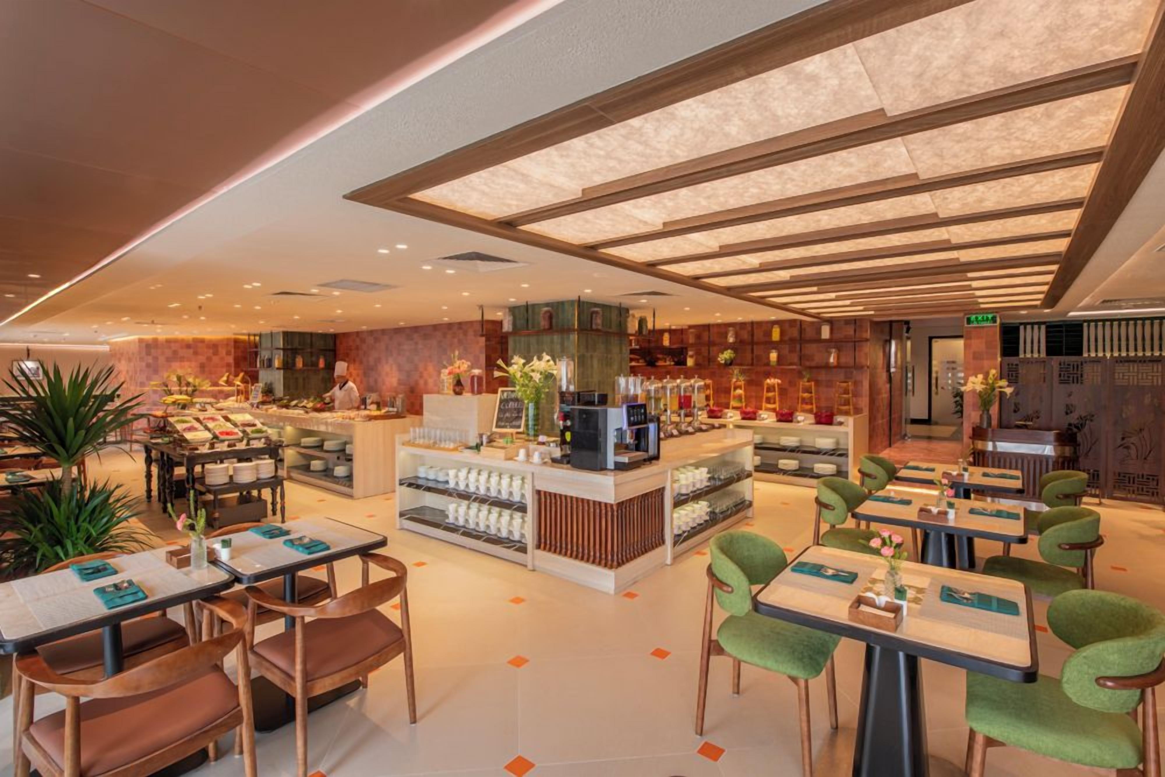 A modern restaurant interior with a central counter, seating area, and decorative plants.
