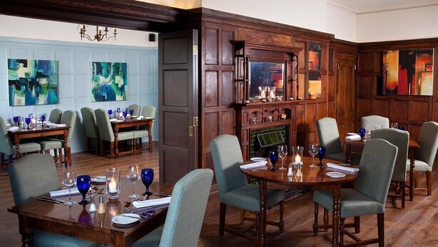 A dining area with wooden tables and chairs, a fireplace, and abstract art on the walls. - Burythorpe House (Malton)