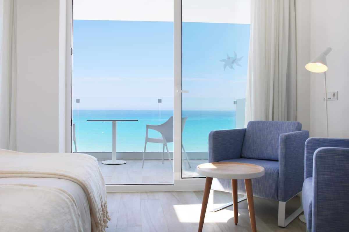 Ein Hotelzimmer mit Balkon, einem Bett, einem kleinen Tisch und zwei Stühlen.