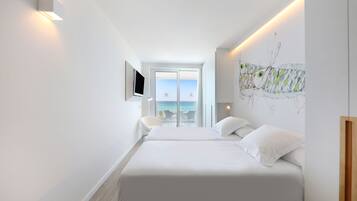 Une chambre d’hôtel moderne avec deux lits, une télévision et un balcon offrant une vue sur la mer.