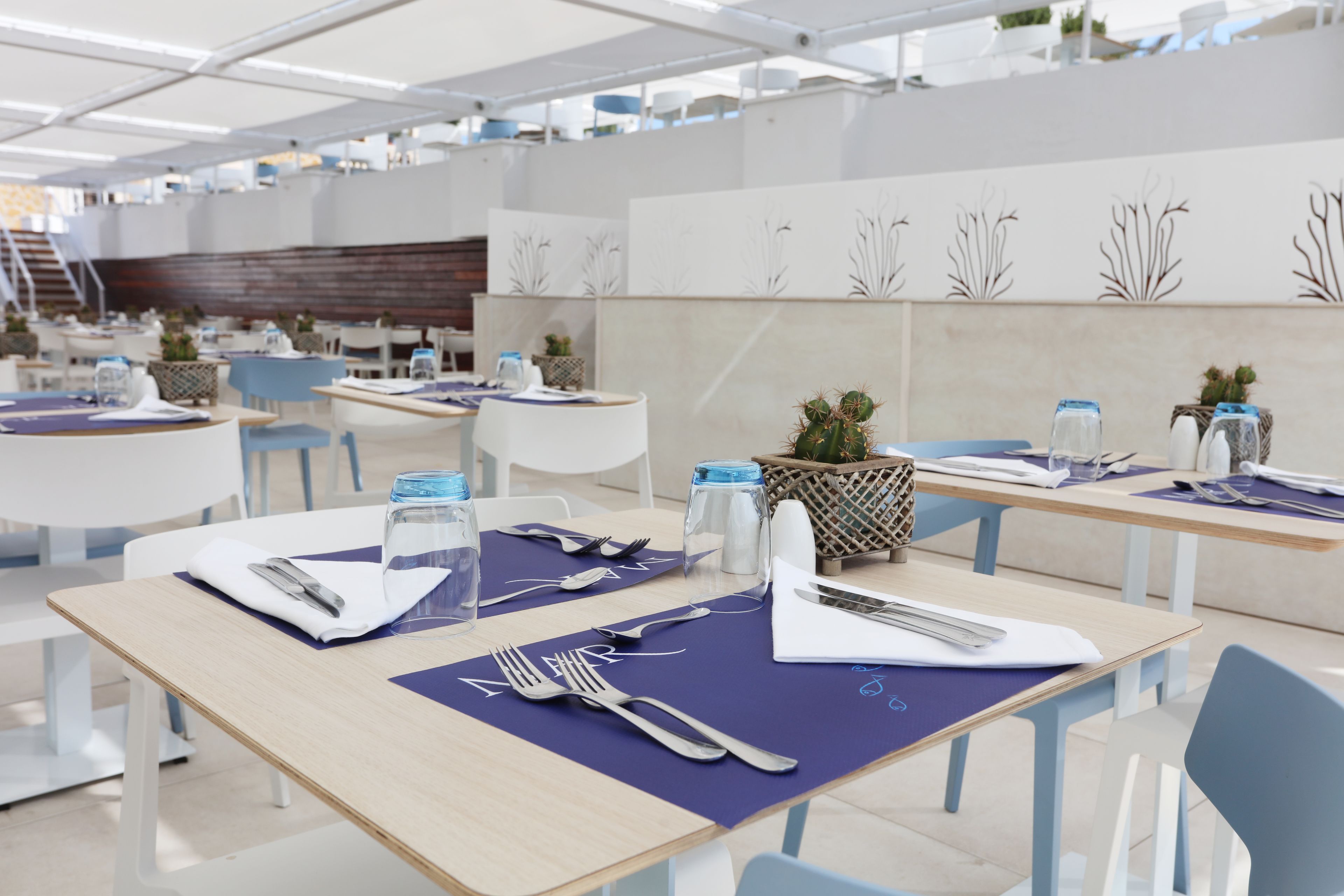 A modern dining area with neatly arranged tables, chairs, and blue placemats.