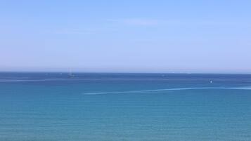 Vista de un mar tranquilo con un velero a lo lejos.