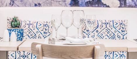 A dining table set with four wine glasses, a small cactus, and a decorative vase.