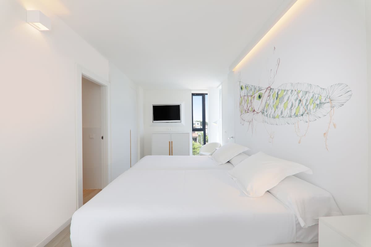 Ein modernes Schlafzimmer mit einem großen Bett, einem Flachbildfernseher an der Wand und einem minimalistischen Design.