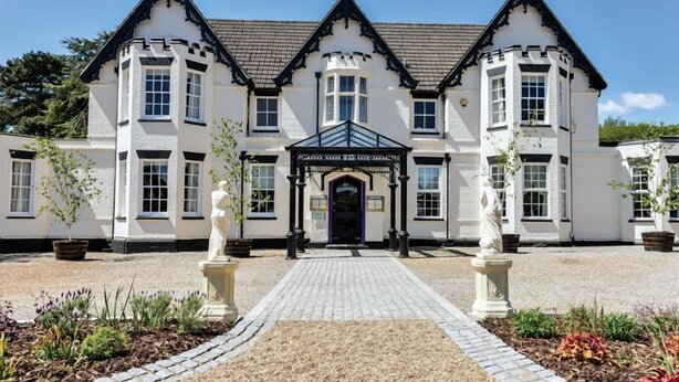 A traditional building with a symmetrical facade, a central entrance with a black door, and a paved walkway leading to it. - The Coach House Suffolk (Lowestoft)