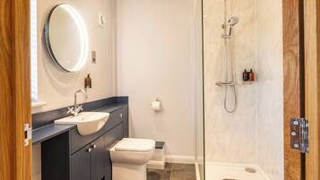 A modern bathroom with a sink, toilet, and glass-enclosed shower.