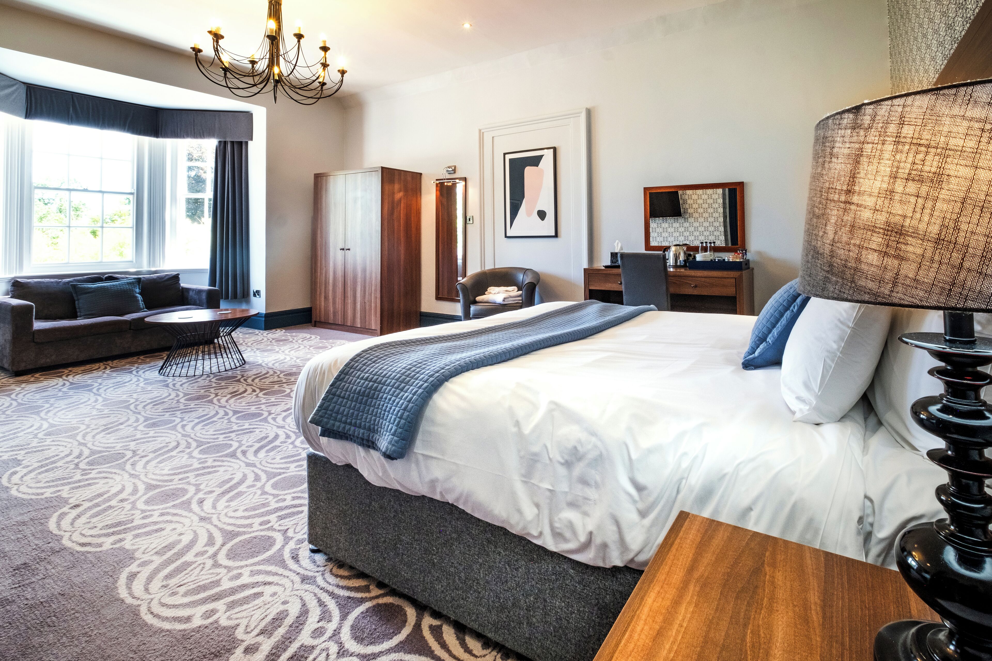 Una habitación de hotel con una cama grande, un sofá, un escritorio y un armario.