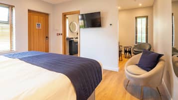 A hotel room with a bed, a TV, a chair, and a bathroom.