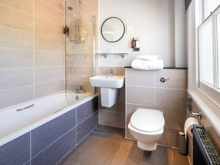 Une salle de bain moderne équipée d’une baignoire, d’un lavabo, de toilettes et d’une douche à parois de verre.