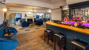 A bar area with stools, a bar counter, and a variety of bottles. - The Coach House Suffolk (Lowestoft)