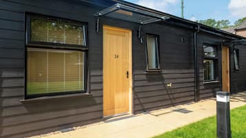 A modern building with a dark exterior, a wooden door labeled '24', and large windows.