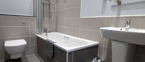 A modern bathroom with a bathtub, toilet, and sink.