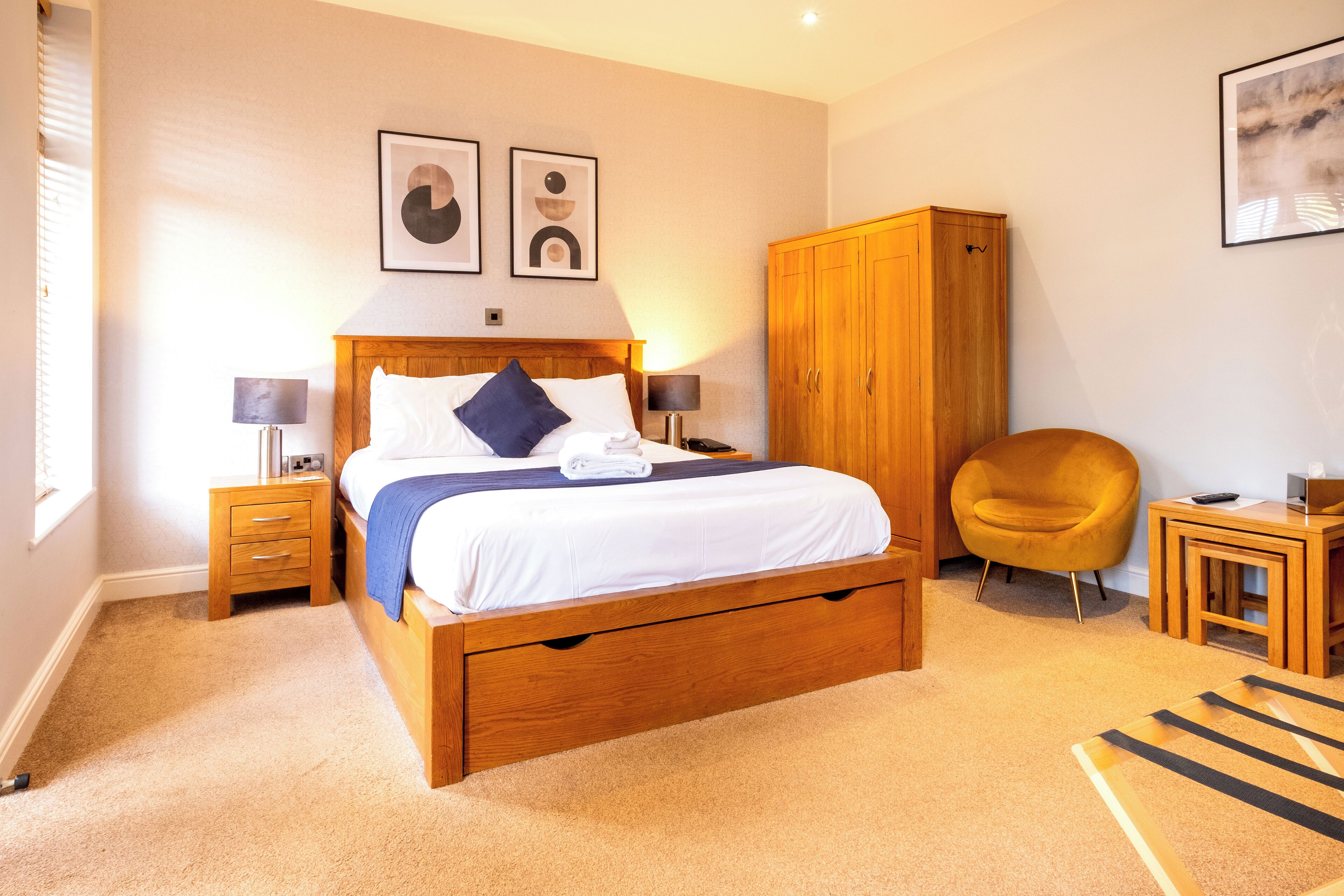 A bedroom with a wooden bed, bedside tables, a wardrobe, a chair, and a small table.