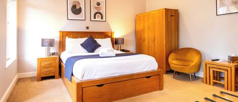 A bedroom with a wooden bed, bedside tables, a wardrobe, a chair, and a small table.